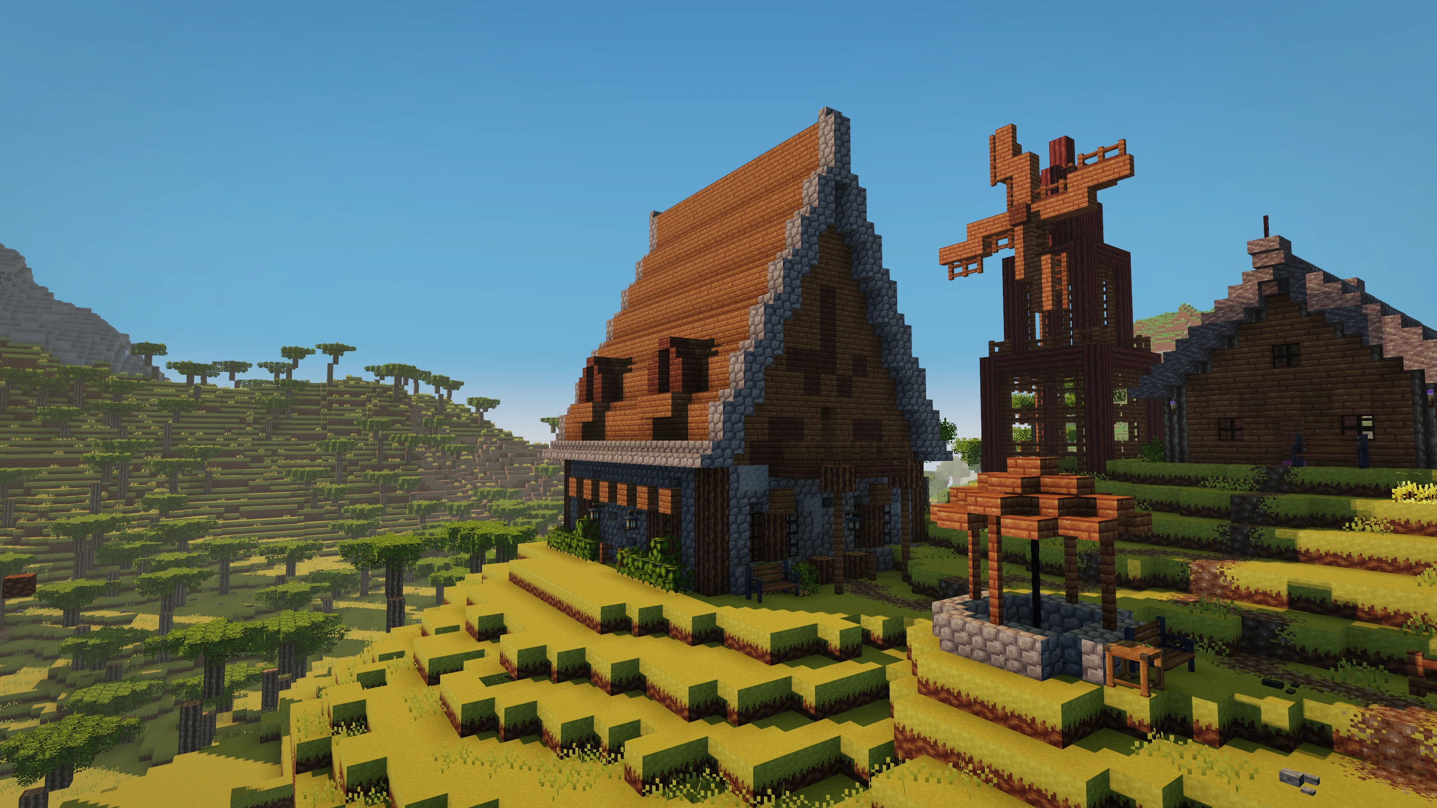 A detailed gabled house with stone trim, timber framing, a windmill, and a covered well