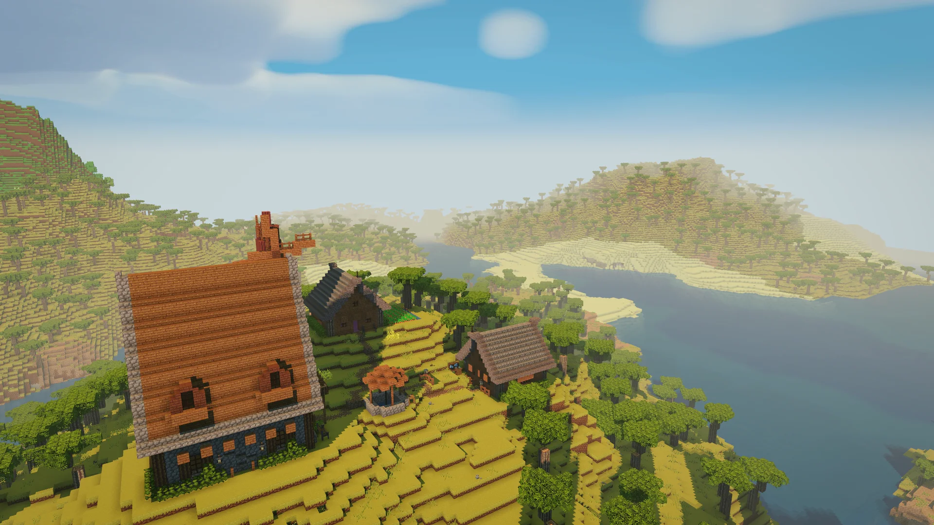 A hilltop village of stone-and-timber houses, a windmill and a covered well above a winding river in Petramond